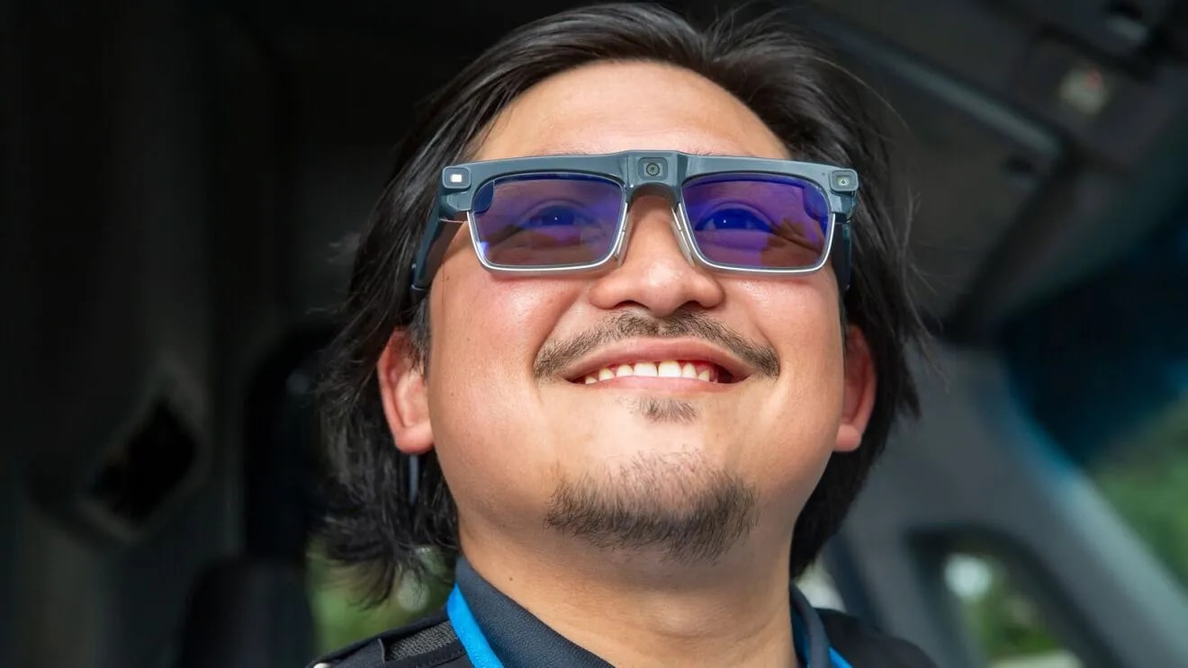 An Amazon delivery courier wearing smart glasses while holding a package.