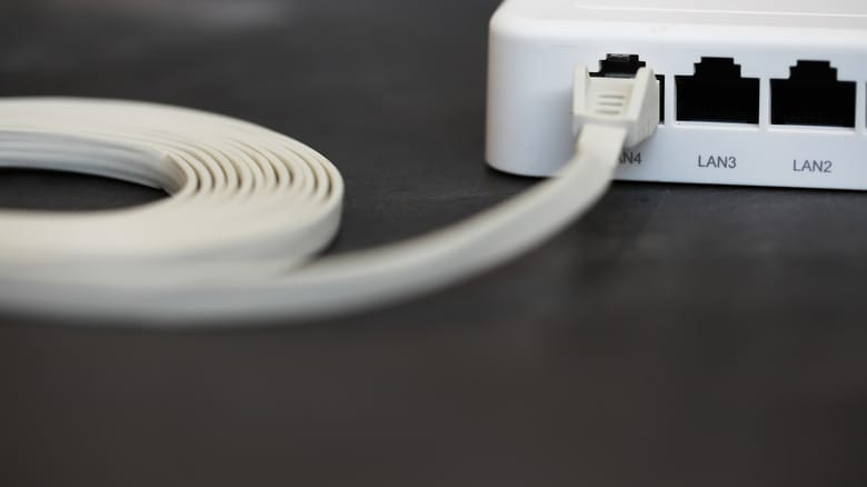 A flat ethernet cable plugged into a port on a router.