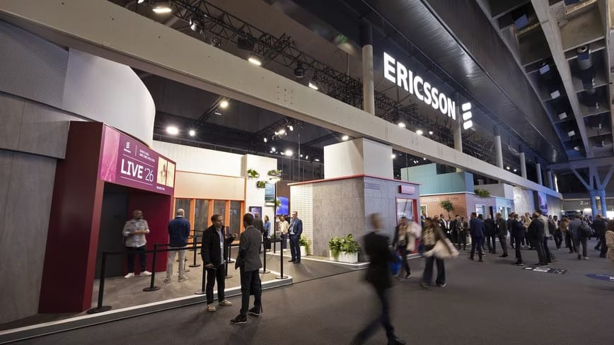 Ericsson’s exhibition stand at MWC Barcelona, with the lit Ericsson logo above and visitors walking past