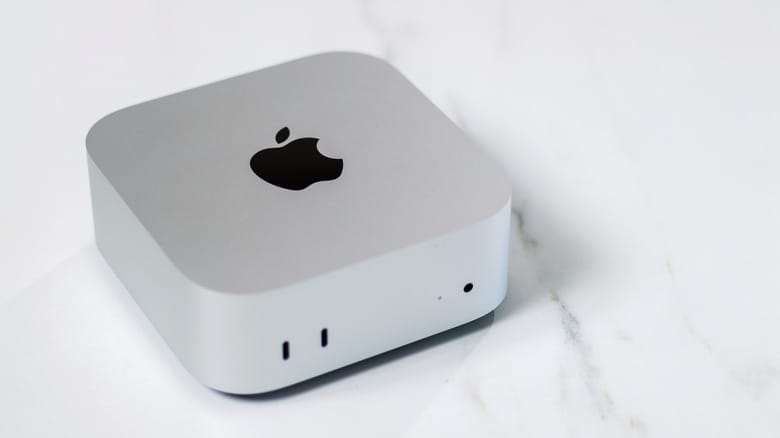Apple's latest silver Mac mini on a table, showing two USB-C ports and audio jack.
