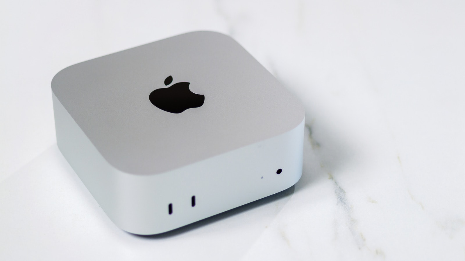 A Mac mini desktop computer sitting on a desk next to a monitor and keyboard.