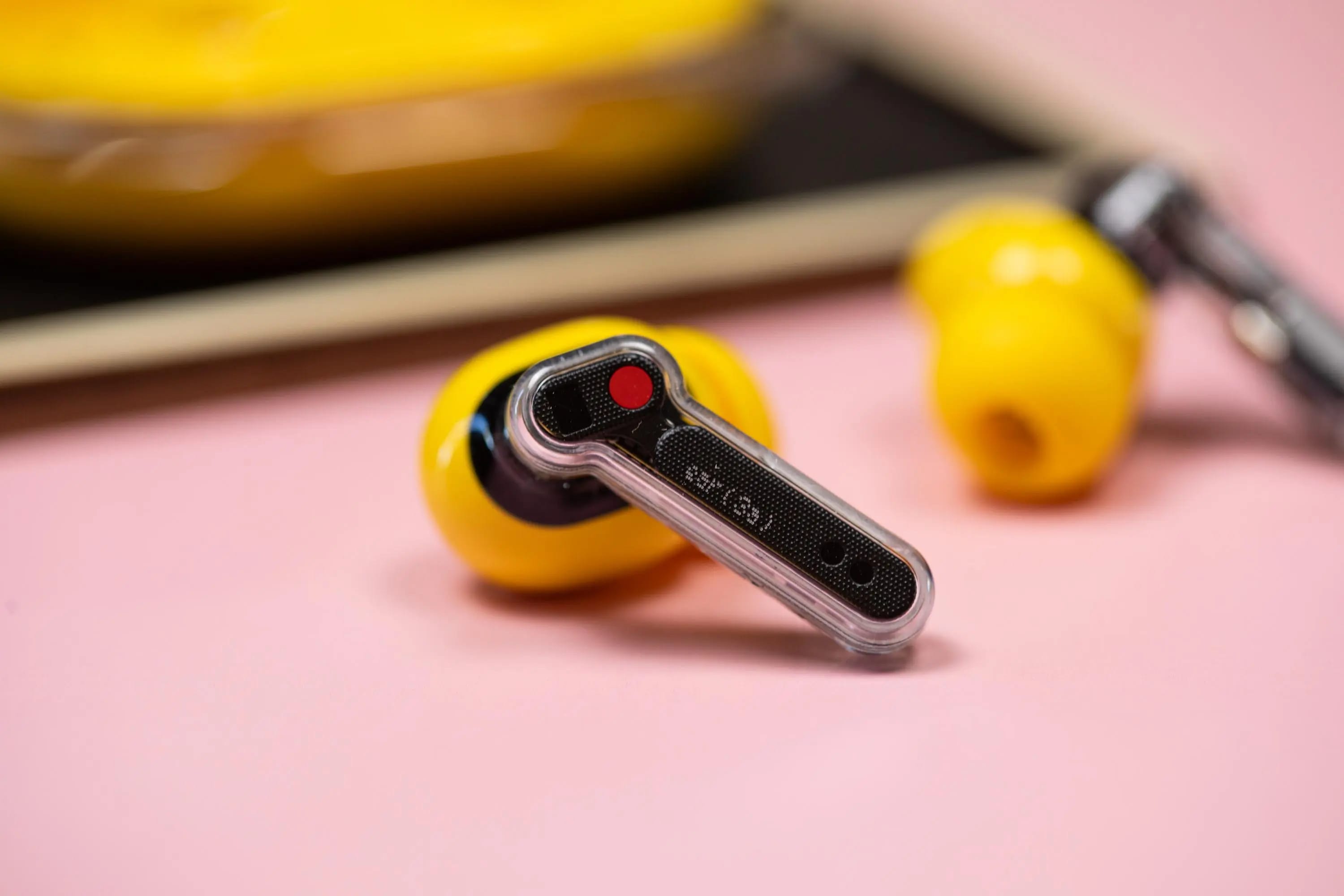The Nothing Ear 3A earbuds on a mauve background with their case.