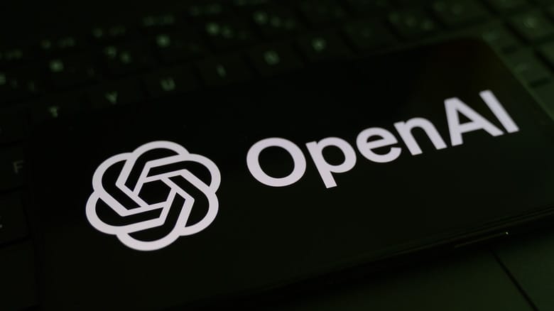 The OpenAI logo on a phone laying on a keyboard.