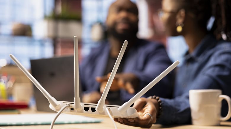 Woman holding a Wi-Fi 7 while sitting at desk.