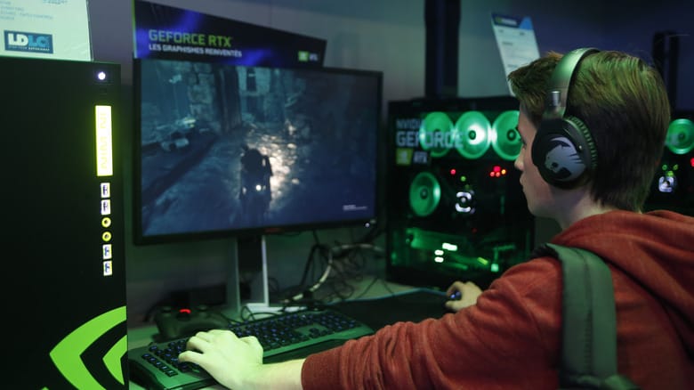 A gamer wearing headphones playing a PC game at an NVIDIA sponsored booth.