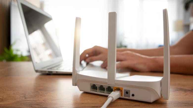 Router placed on a table with person typing on a laptop in the background