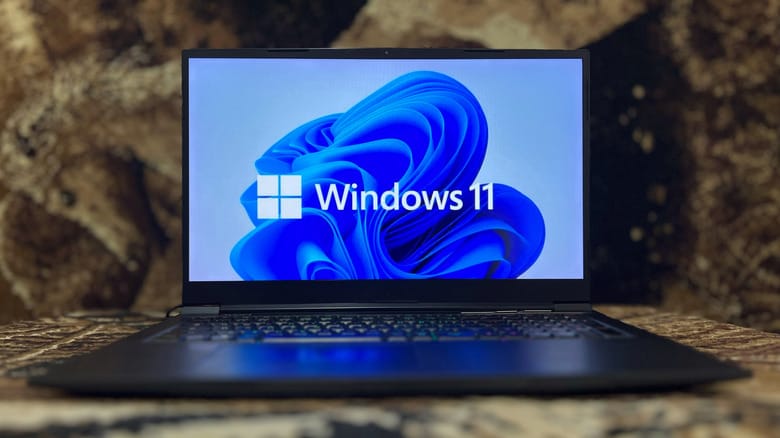 A laptop open to a screen showing the Windows 11 logo.