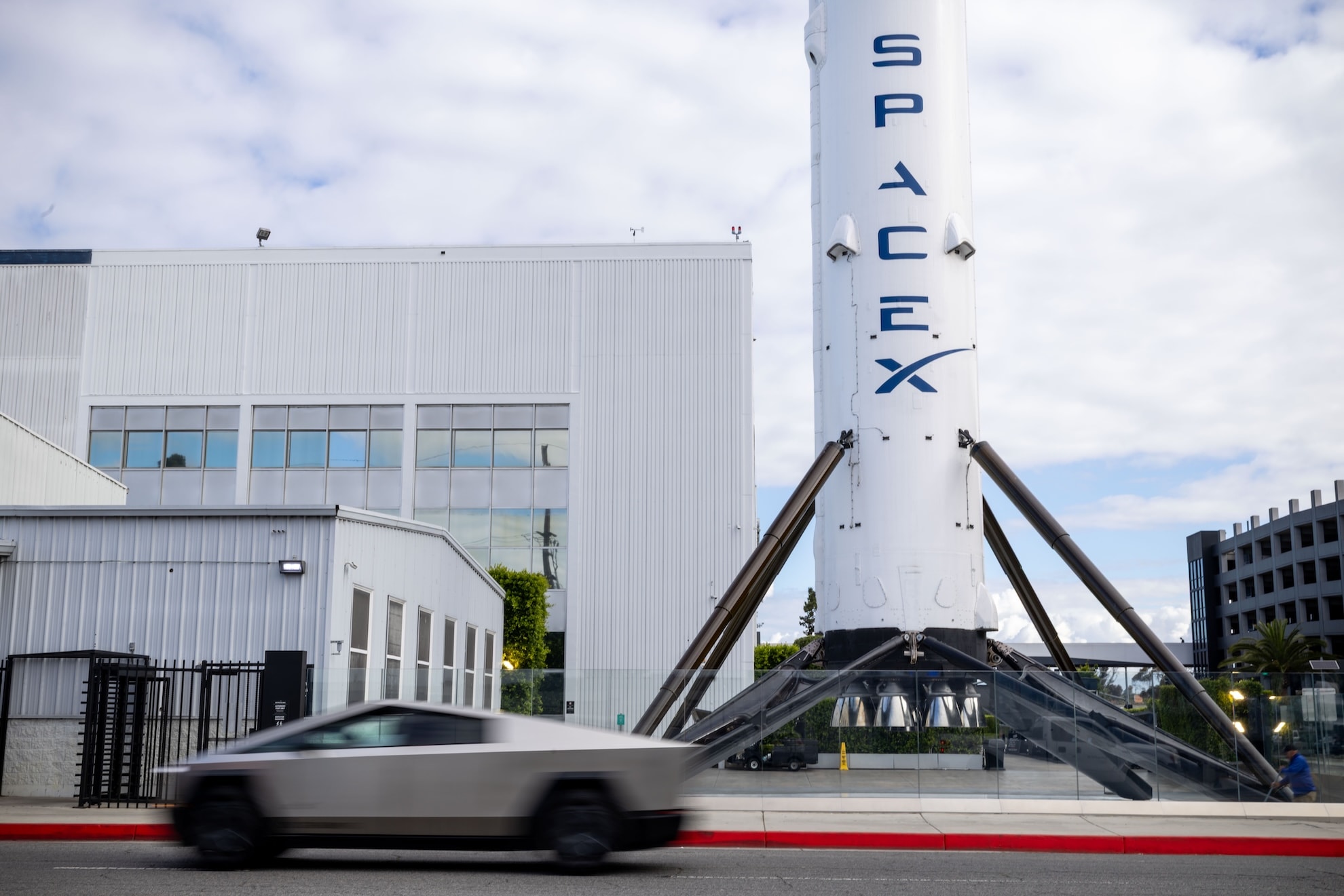 Elon Musk standing in front of Tesla and SpaceX logos
