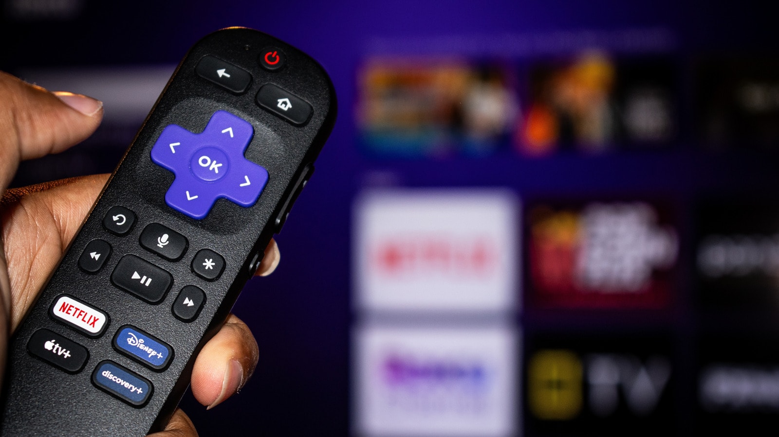 Roku TV remote control resting near a television screen showing picture settings menu